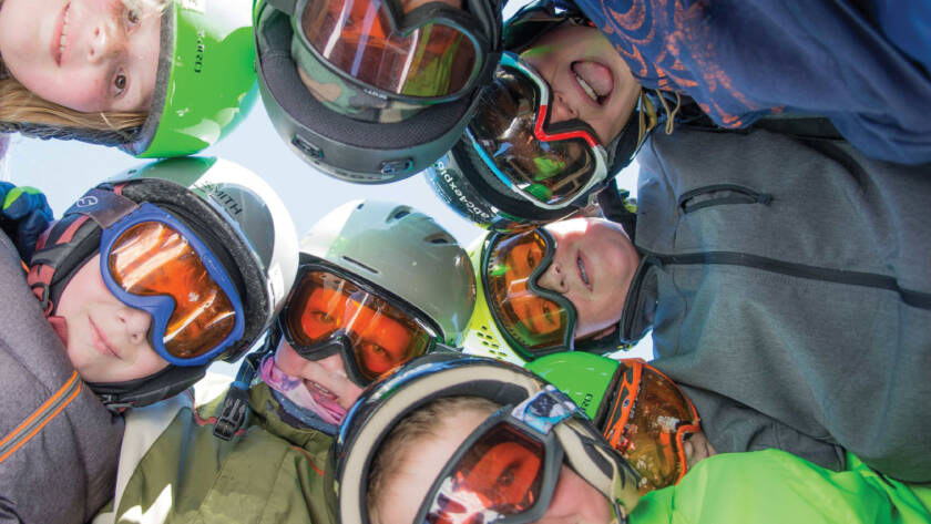 Group of young snow sports enthusiasts looking down at camera