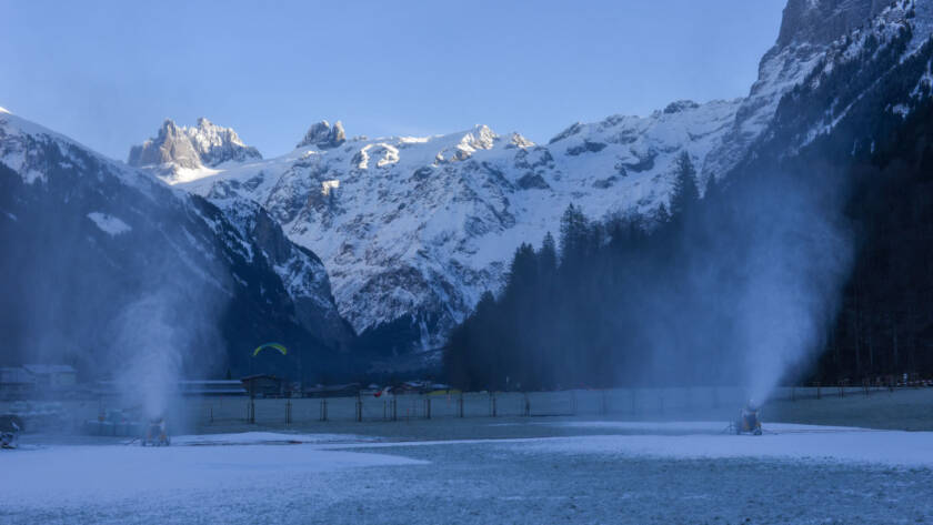 Snowmaking machines with mountainside in background