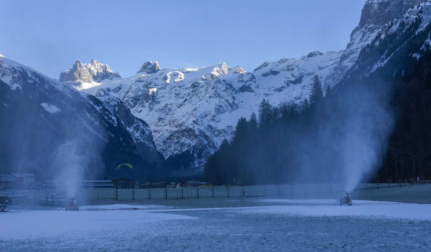 Snowmaking machines with mountainside in background