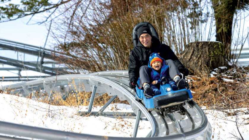 Man riding roller coaster style ride with son