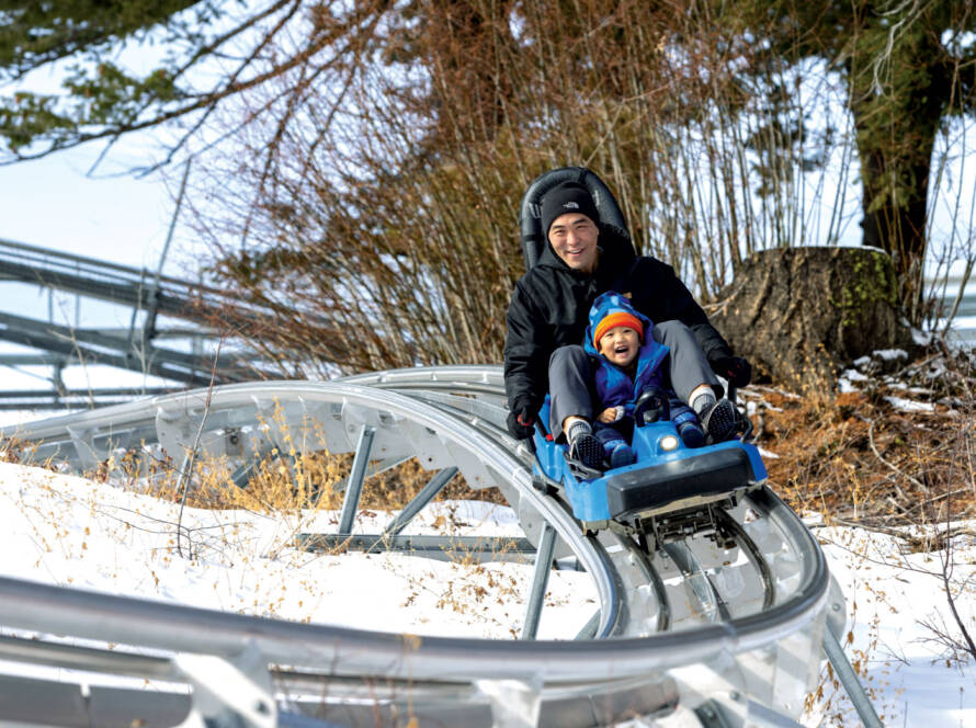 Man riding roller coaster style ride with son