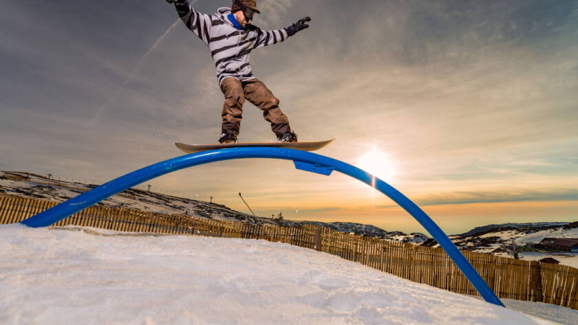 Snowboarder riding rail obstacle