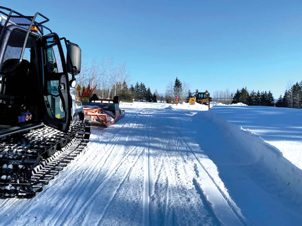 Snow grooming machine parked on trail