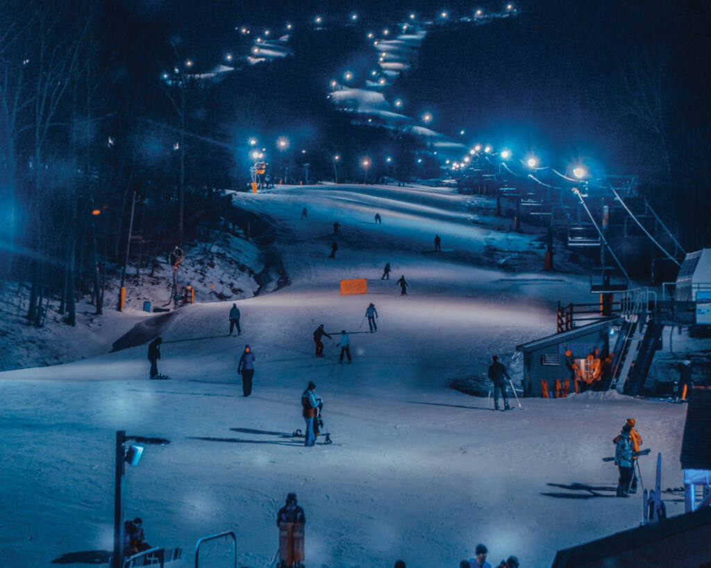 Skiers at night with lights on slopes