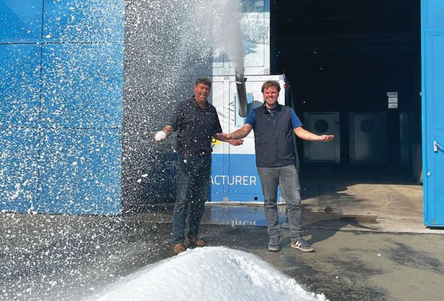 Albert Bronander and Roberto Penocchio standing in front of snow blowing machine