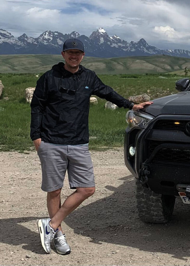 Photo of Scott Jones in shorts leaning against vehicle