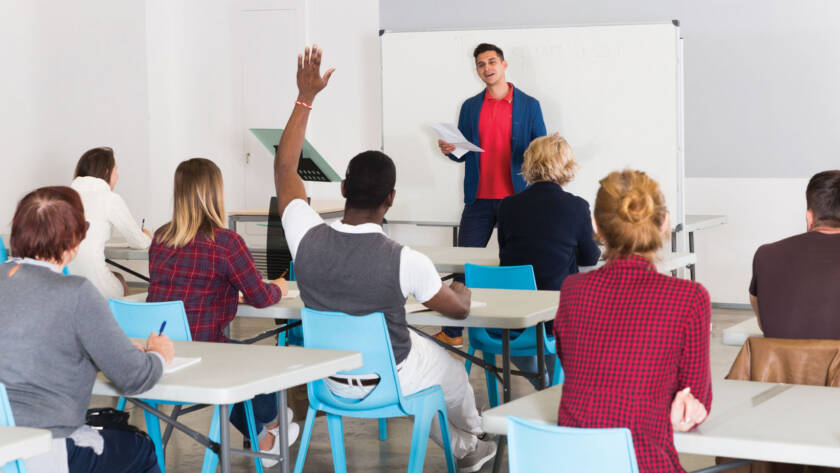 Teacher in class with student raising hand to ask a question