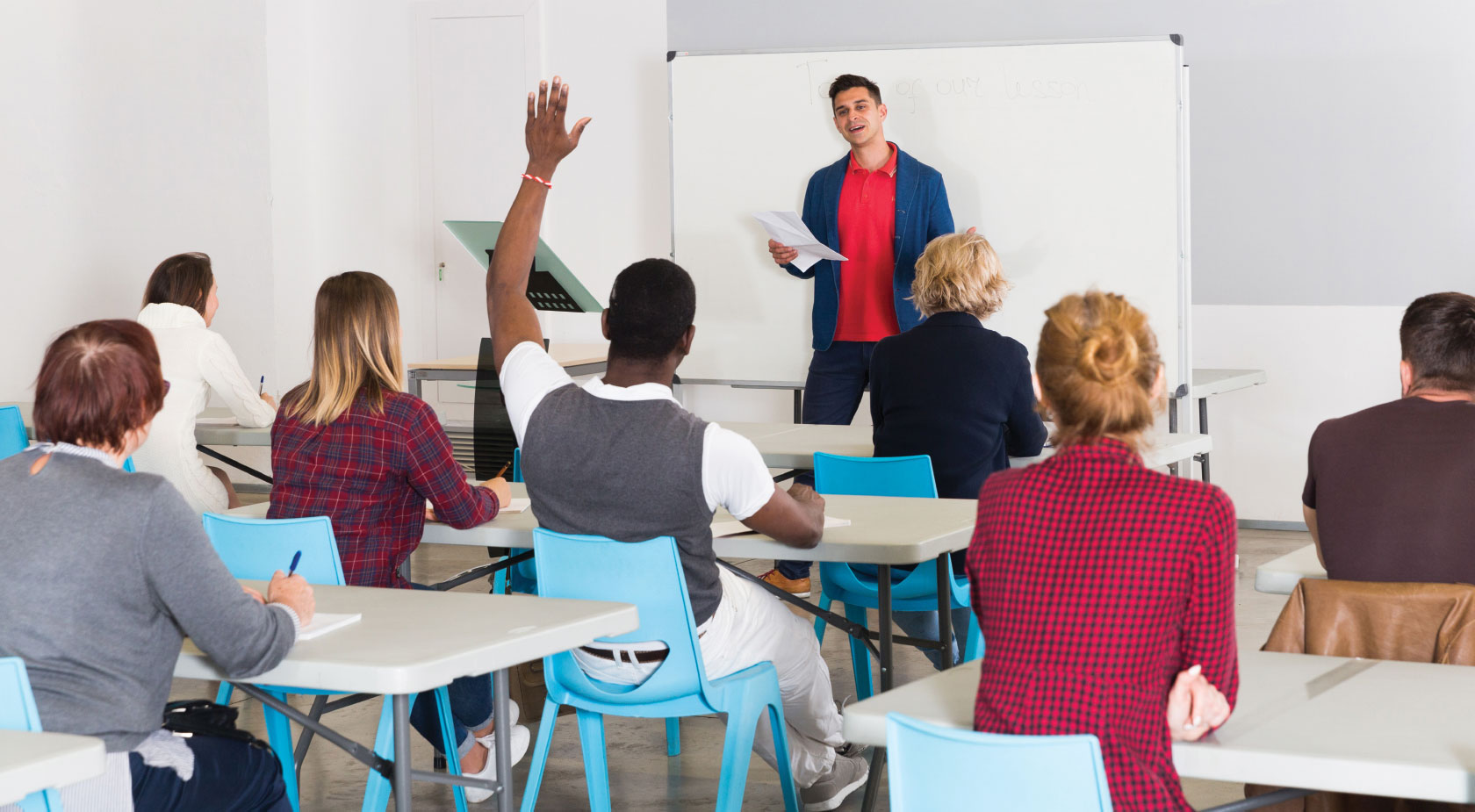 Teacher in class with student raising hand to ask a question