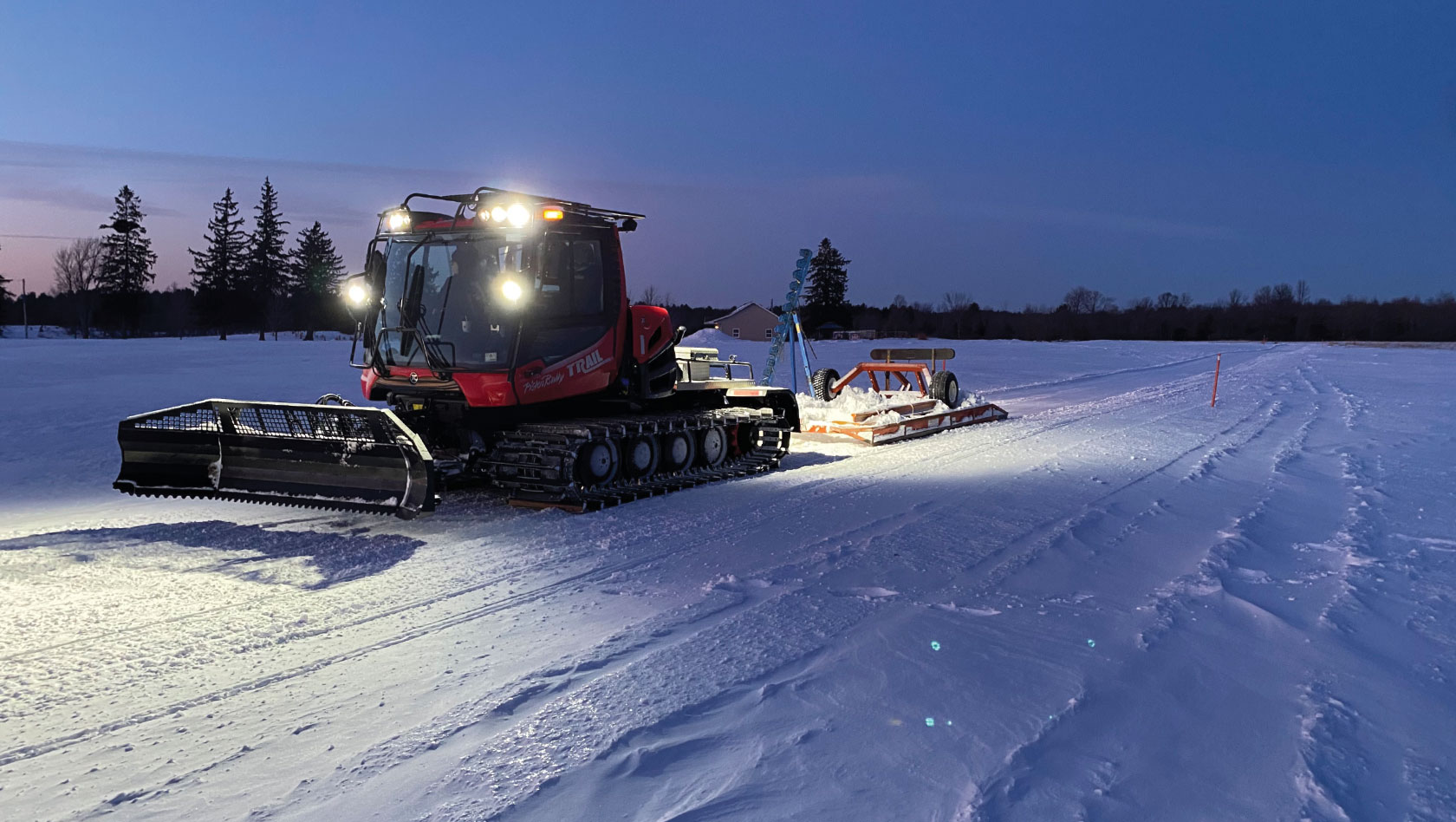 PistenBully snow groomer with a Mogul Master drag, a brush bar and packer