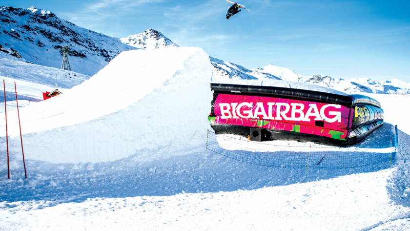 Snowboarder jumping off ramp on to BigAirBag