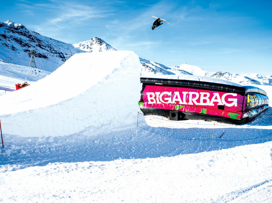 Snowboarder jumping off ramp on to BigAirBag