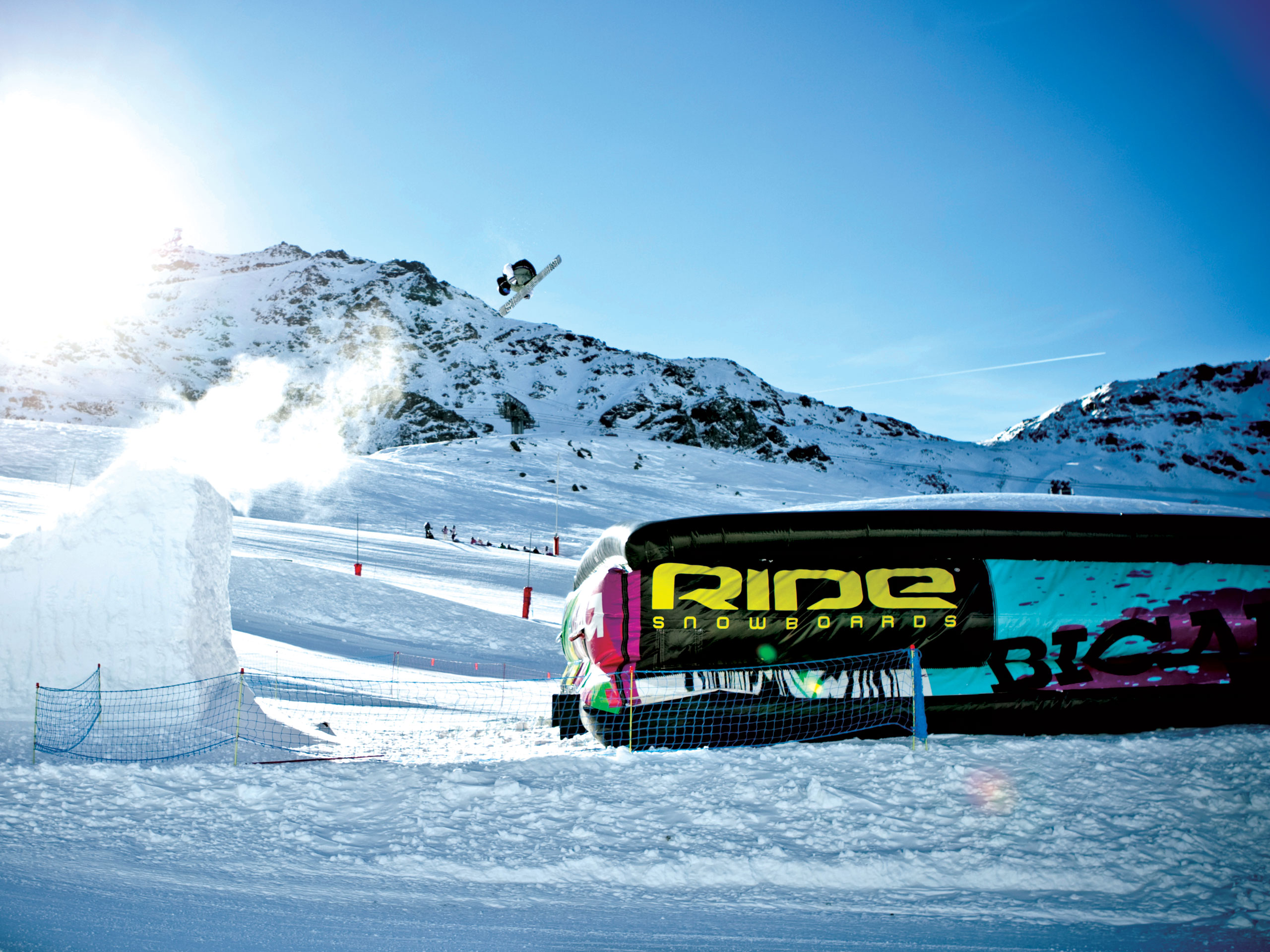 Snowboarder jumping off ramp on to BigAirBag