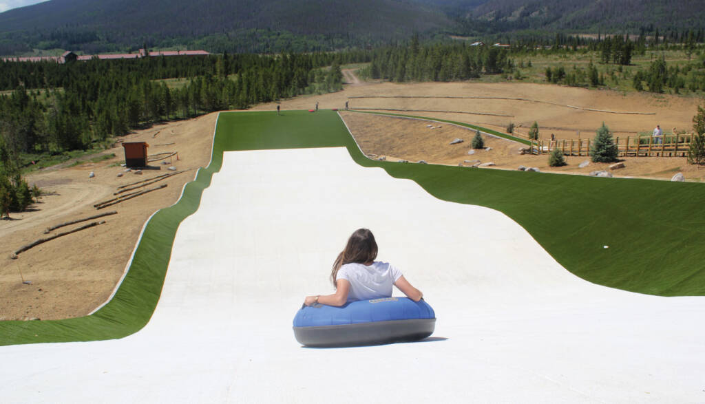 Child on tube going down Snowflex slide