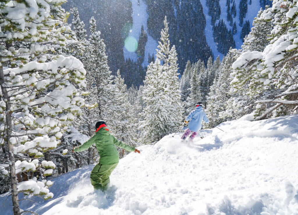 Skier and snowboarder going down run