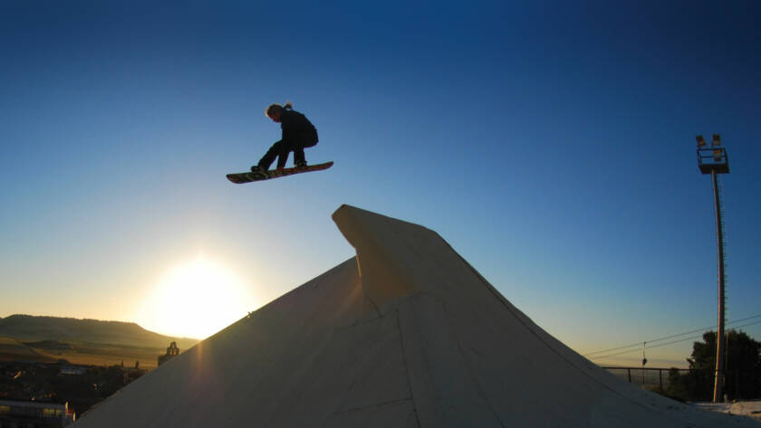 Snowboarder jumping off ramp