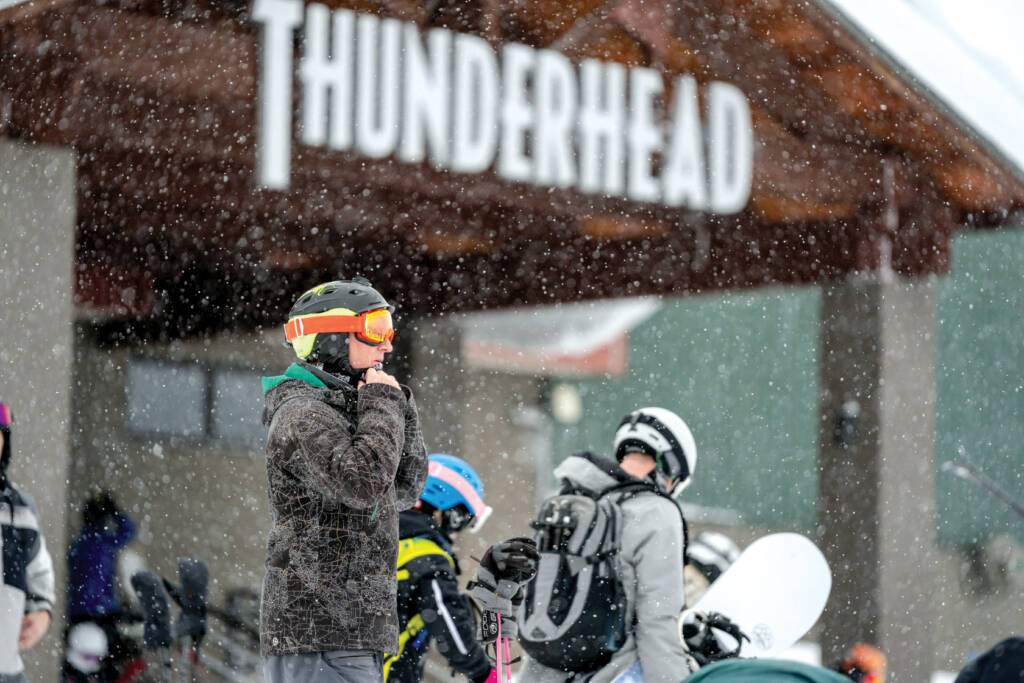 Skier strapping helmet on with Thunderhead in background.