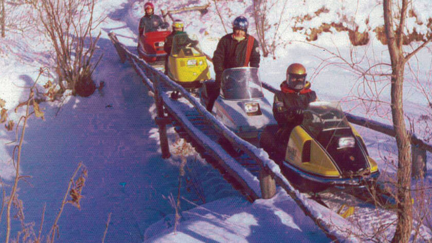 Photo of riders on snowmobiles on footbridge