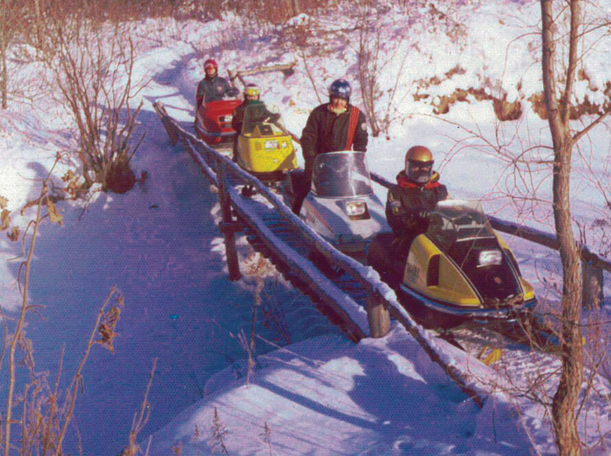 Photo of riders on snowmobiles on footbridge