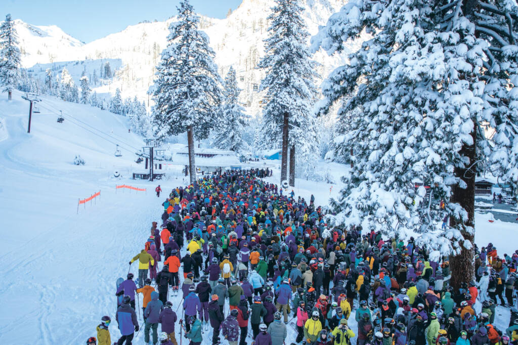 Large group of skiers and snowboarders in line for chair lift