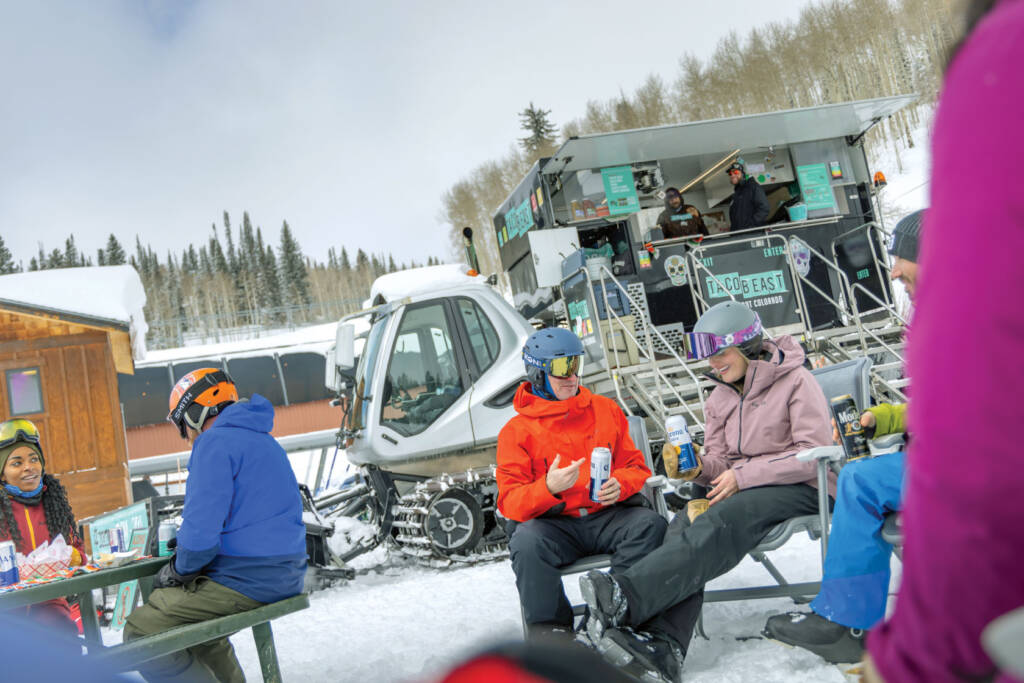 Snowboarders eating and drinking.