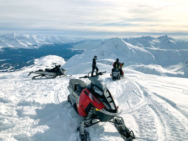 Snowmobilers with snowmobile in foreground