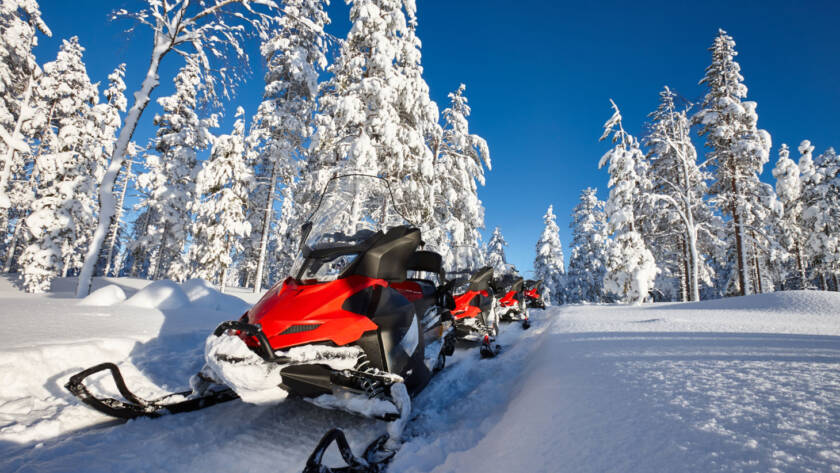 Snowmobile on trail with snow covered trees in background