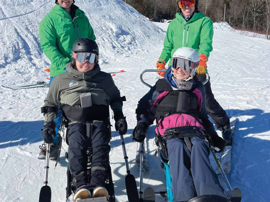 Four skiers in snow gear and specialized ski equipment