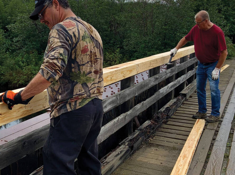 Two men repairing bridge railing