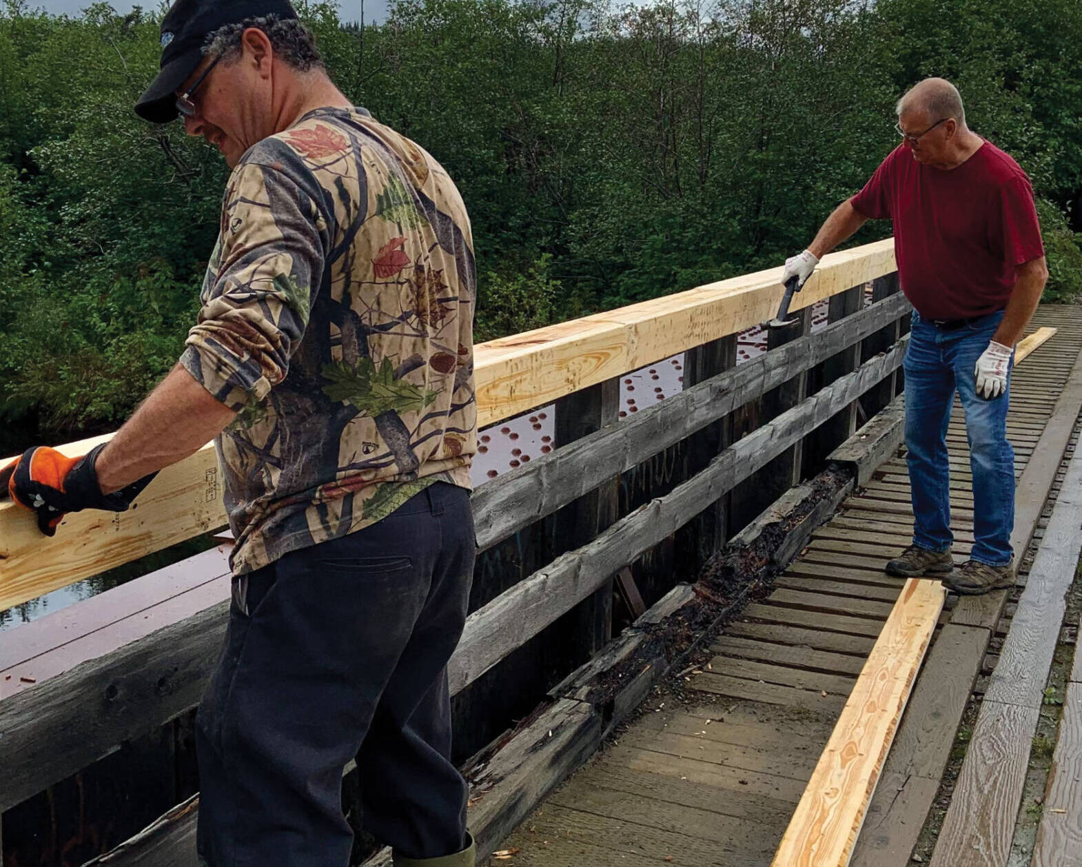 Two men repairing bridge railing