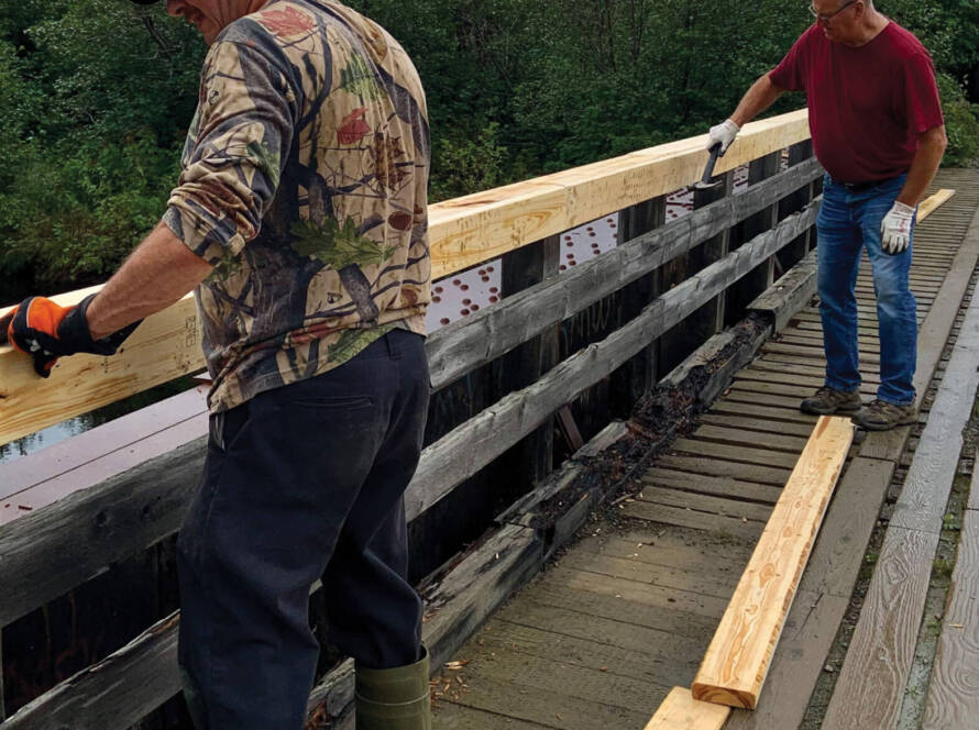 Two men repairing bridge railing