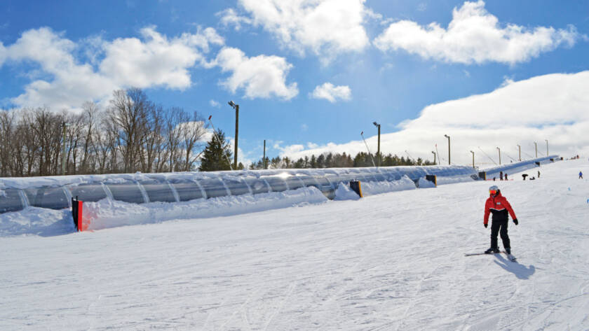 Skier on slope with Team Service moving carpet in background