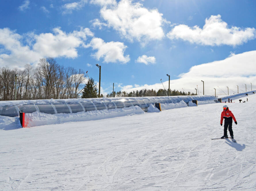 Skier on slope with Team Service moving carpet in background