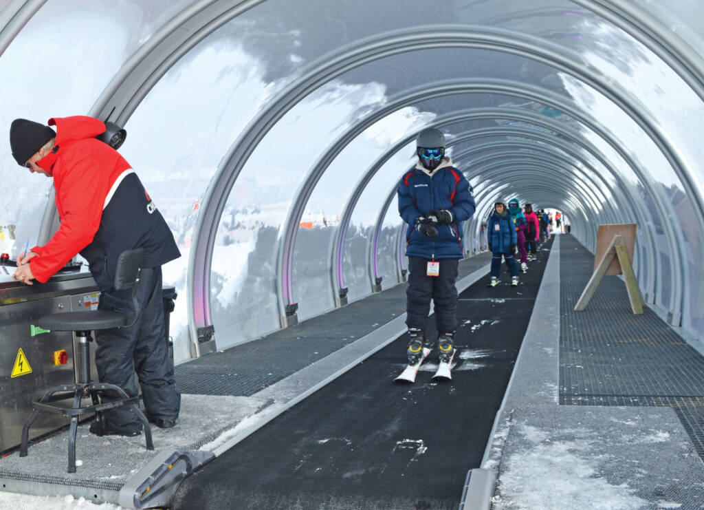 Young skiers on TS-Premium model carpet lift with operator at the controls