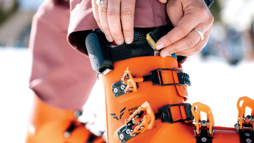 Closeup of a Carv device being strapped onto a bright orange snow boot