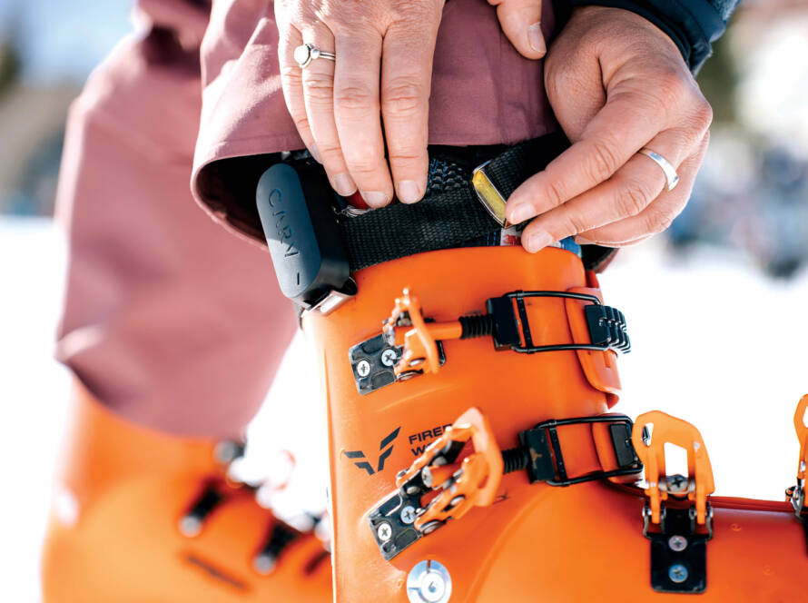 Closeup of a Carv device being strapped onto a bright orange snow boot