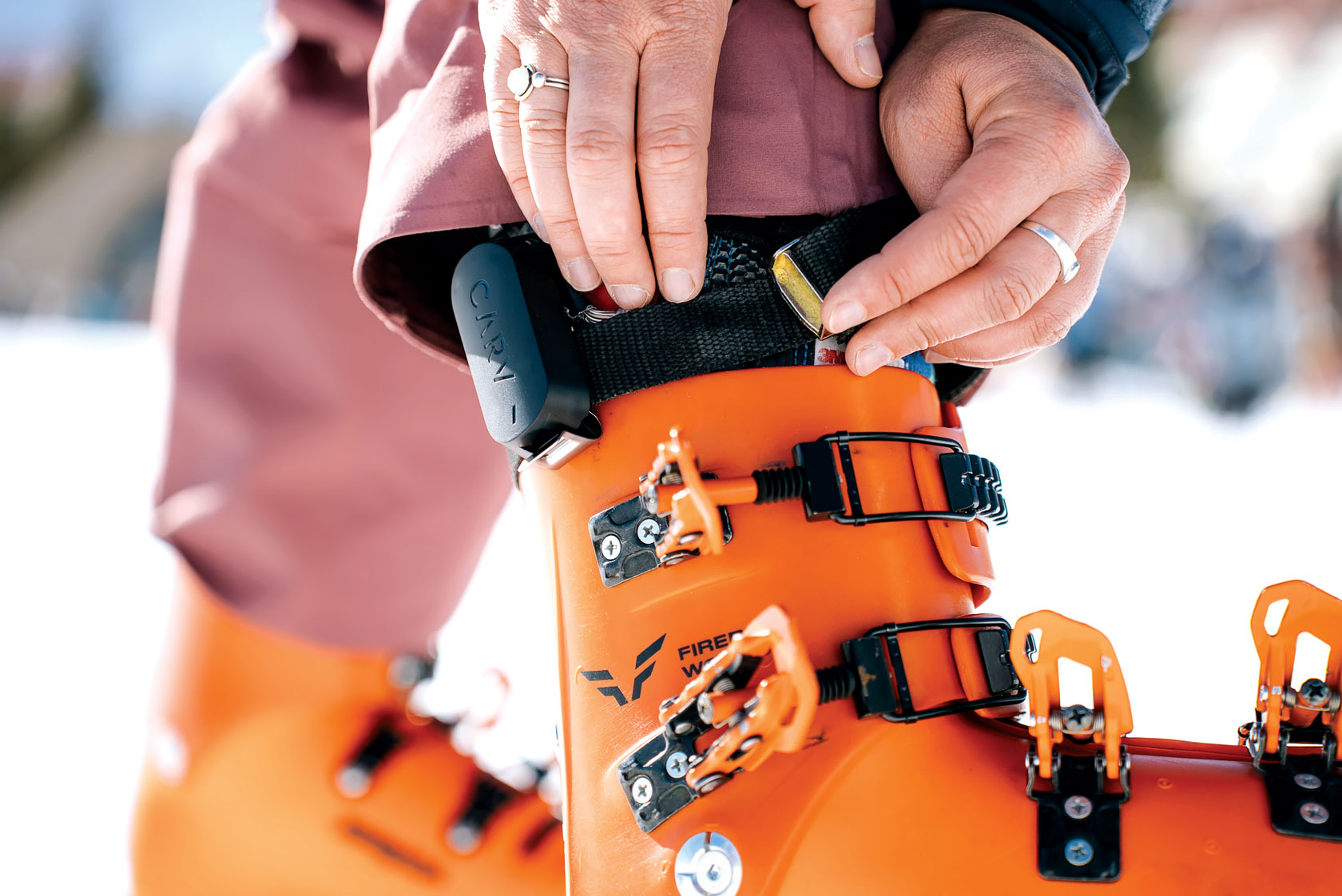 Closeup of a Carv device being strapped onto a bright orange snow boot