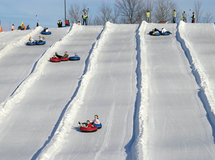 Adults and children going down ski slope in tubes