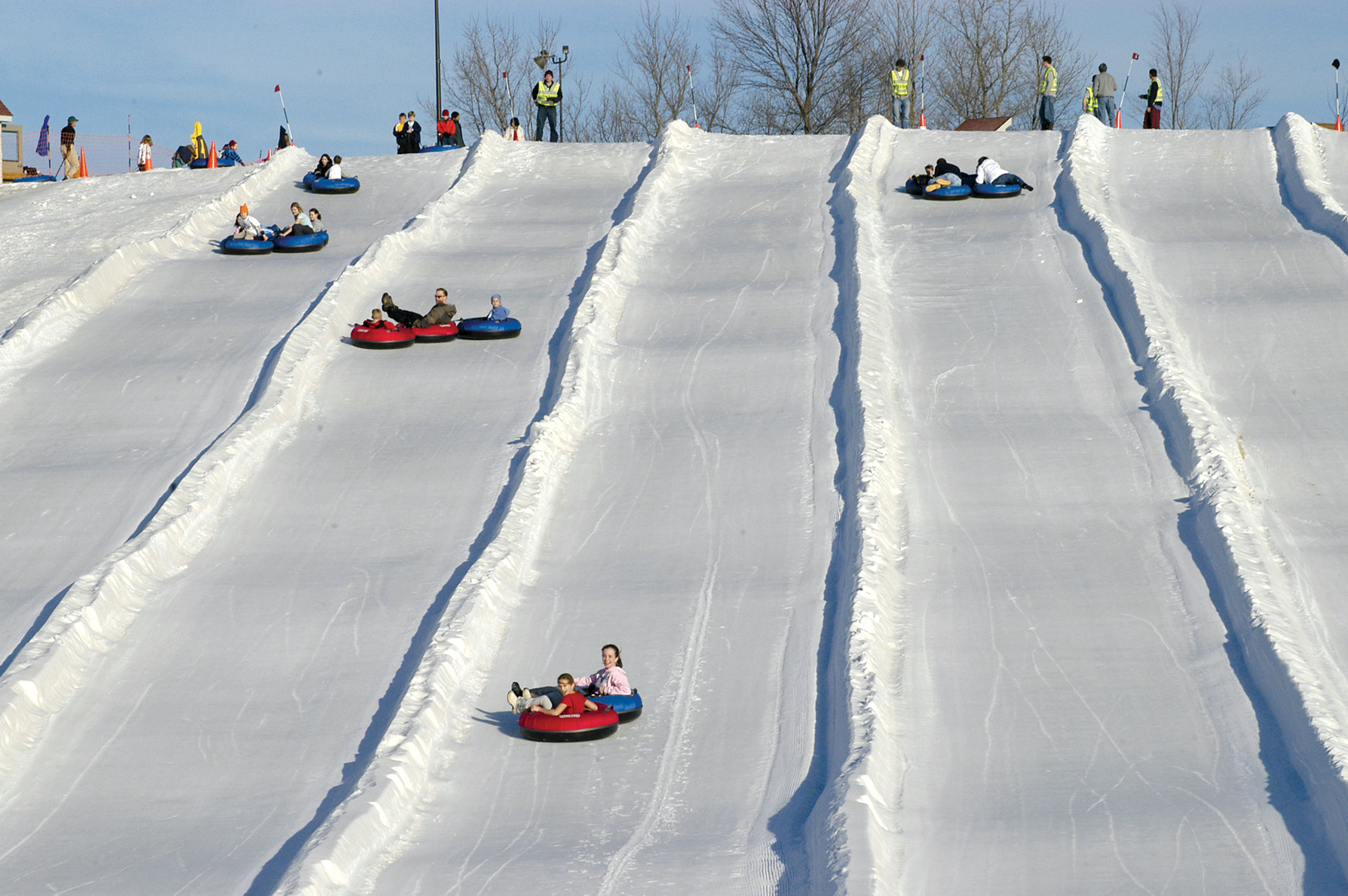 Adults and children going down ski slope in tubes