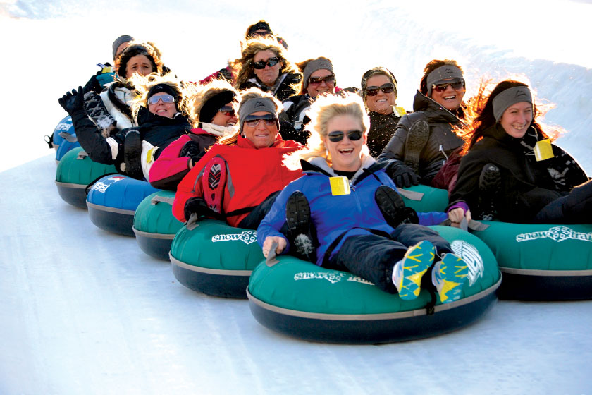 Adults and children sitting in snow tubes