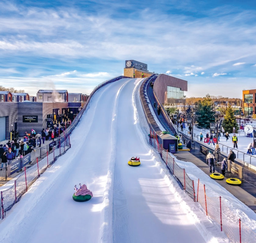 Adults and children going down ski slope in tubes