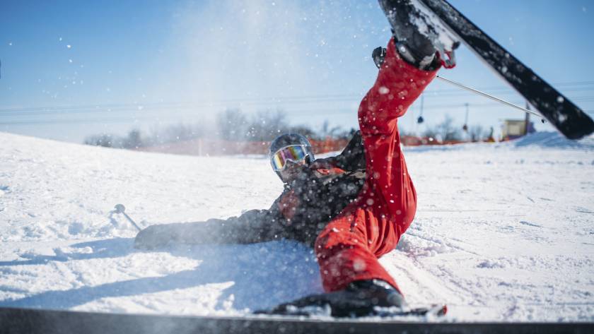 Skier in helmet and glasses lies on snowy mountain