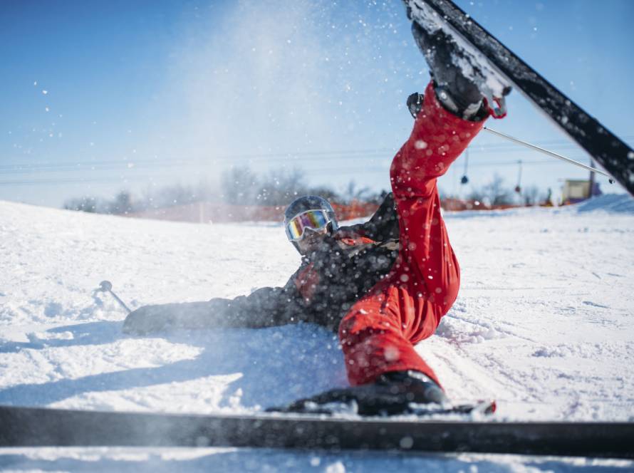 Skier in helmet and glasses lies on snowy mountain