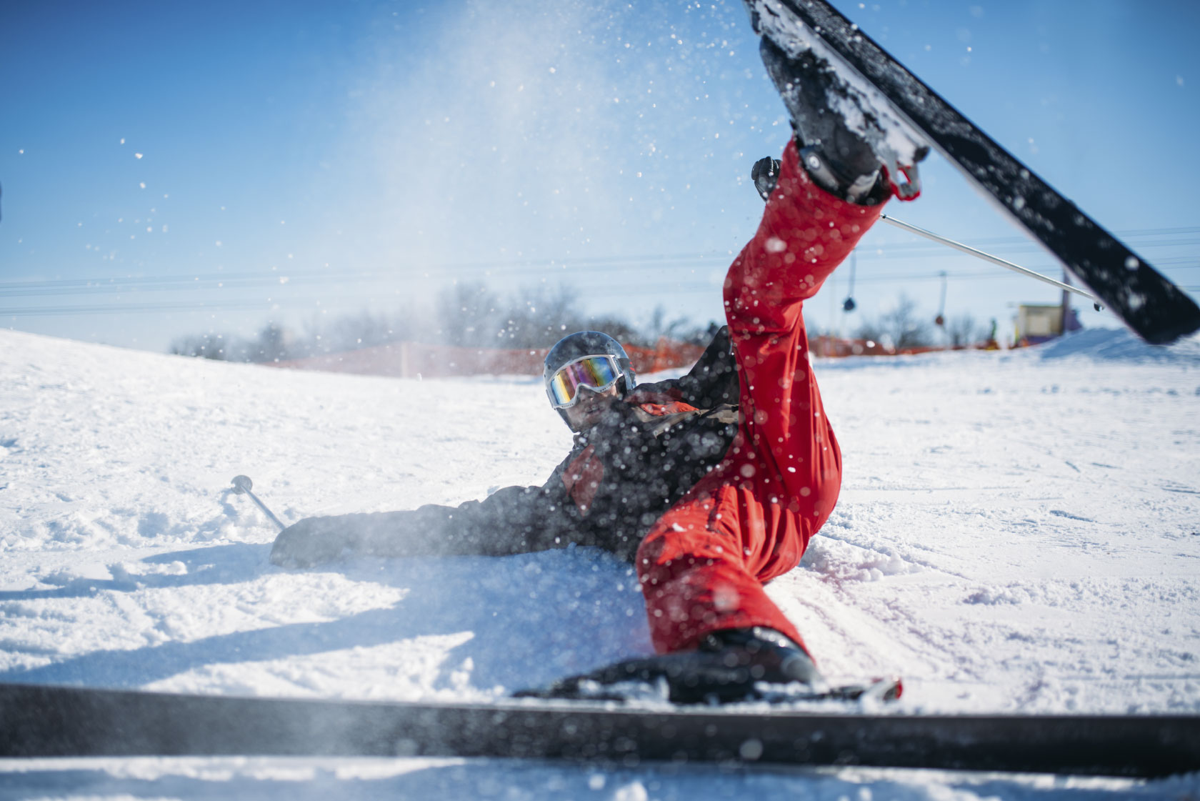 Skier in helmet and glasses lies on snowy mountain