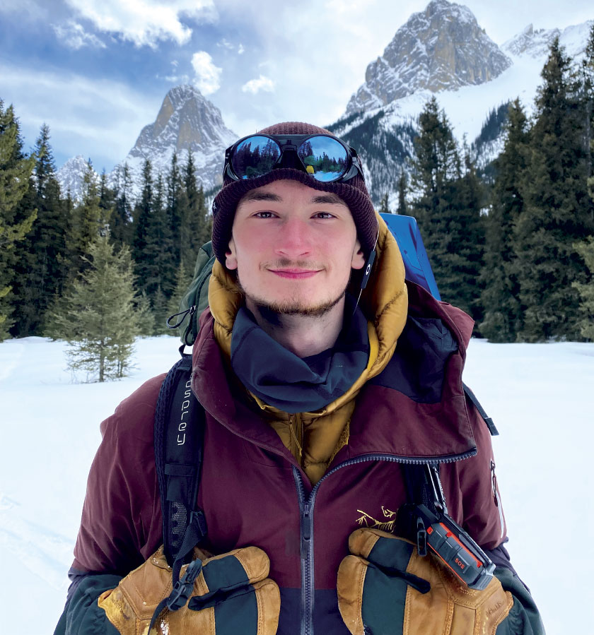 Matthew Sheahan posing for photo with snow-covered mountains in background