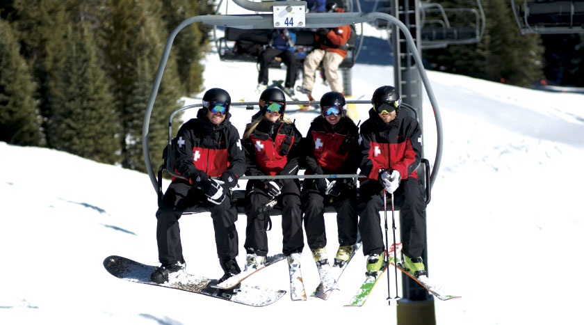 Four National Ski Patrol patrollers on chairlift