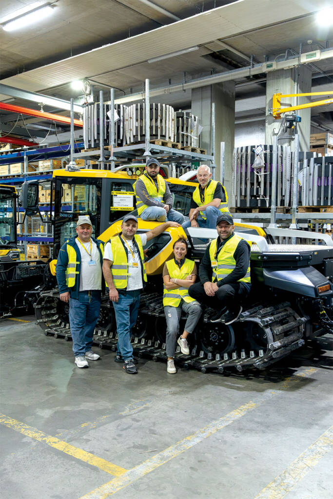 Group posing for photo in front of snowcat