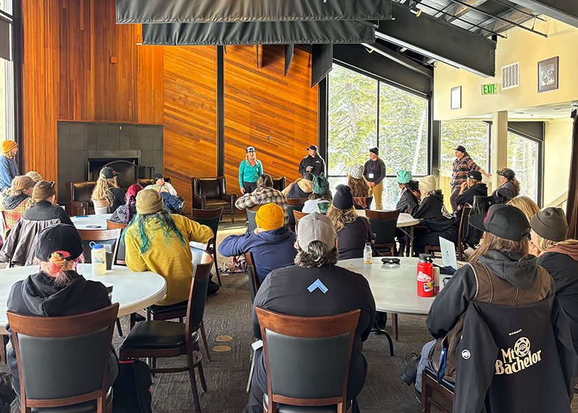 Crowd seated at tables listening to speakers