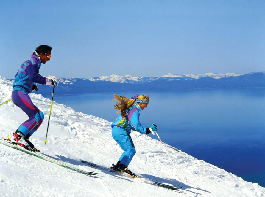 Side profile of two skiers going down mountain