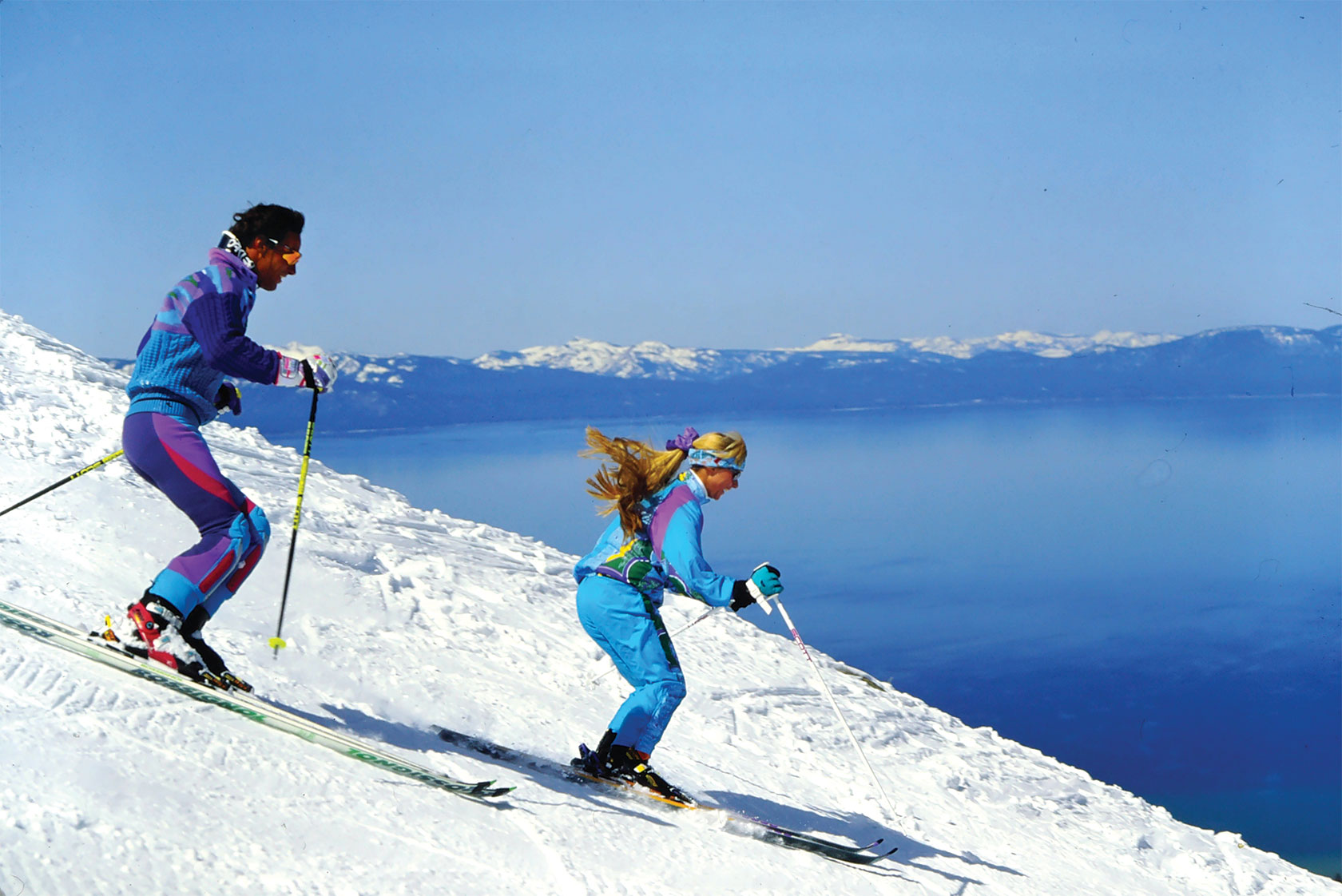 Side profile of two skiers going down mountain