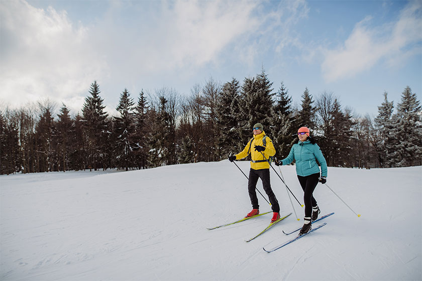Couple skiing together, treeline in background